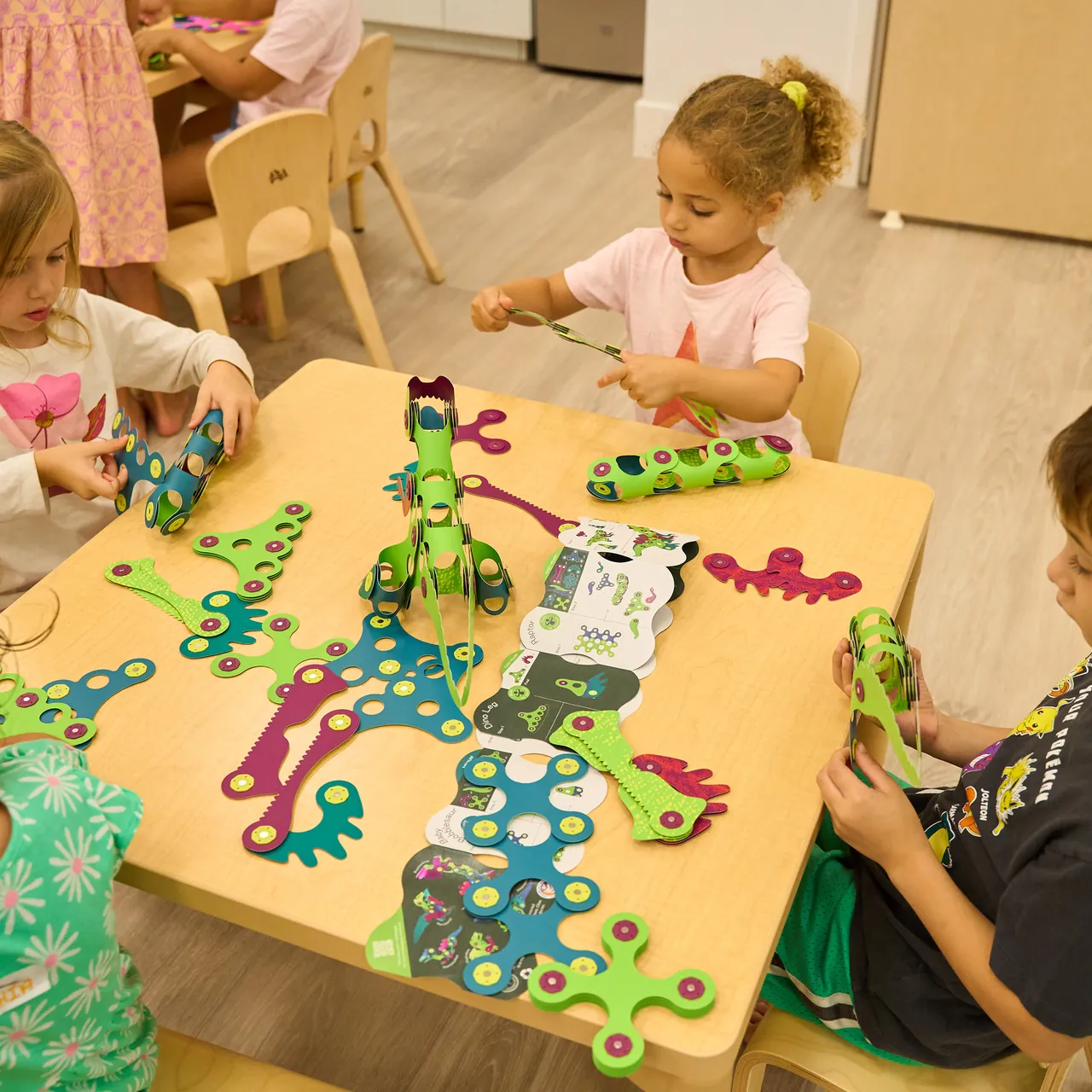 Children building Clixo dinosaurs together at a classroom table